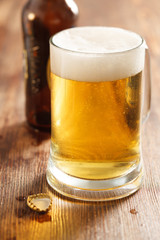 cold beer glass on bar or pub desk, bottle of beer on background
