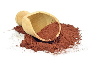 A wooden scoop with cocoa powder on a white background