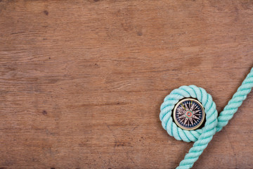 Compass and rope on wooden texture background