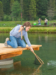 Junge angelt - keschert Forelle am Fischteich