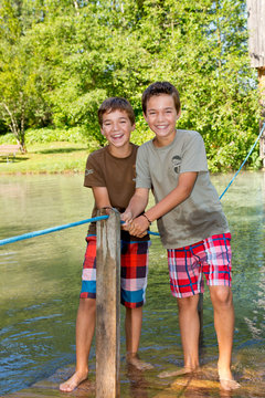 Zwei glückliche Freunde überqueren einen Bach mit dem Floß