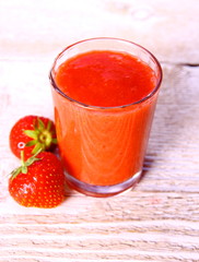 Strawberry smoothie in glass with two berries