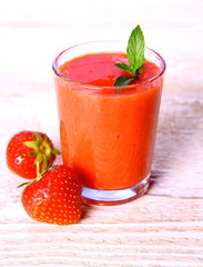 Strawberry smoothie in glass with two berries and mint