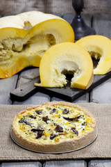 Quiche lorraine on wooden table among pumpkins