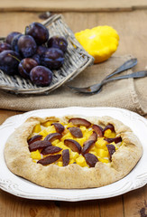 Pumpkin, plum and apricot galette on wooden table