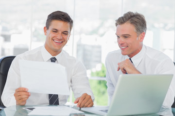 Obraz na płótnie Canvas Smiling businessman listening to his intern while explaining doc