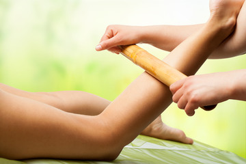 Bamboo massage on female leg.