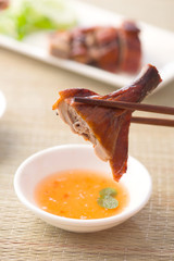 chopstick holding chinese roast duck served with soya sauce and
