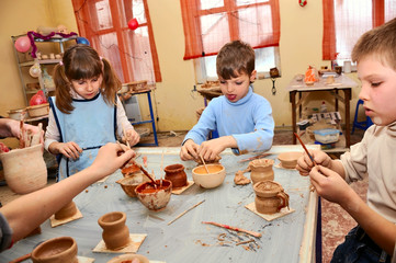 group of children decorating their clay pottery