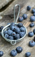 blueberries in a small colander on wooden background