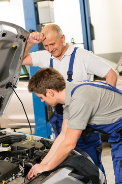 Elderly mechanic supervising  colleague's work