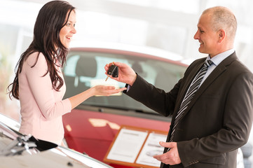 Salesman handing car keys to woman