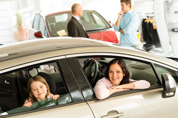 Mother and daughter trying car in dealership