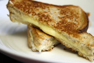 Oozing grilled cheese sandwich on white plate