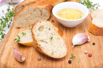 baguette with herbs, oil, spices and garlic on a wooden board