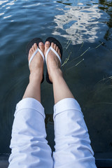 Feet Wearing White Flipflops Hanging Over a Lake