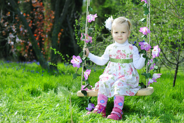 beautiful little girl on a swing in a beautiful dress