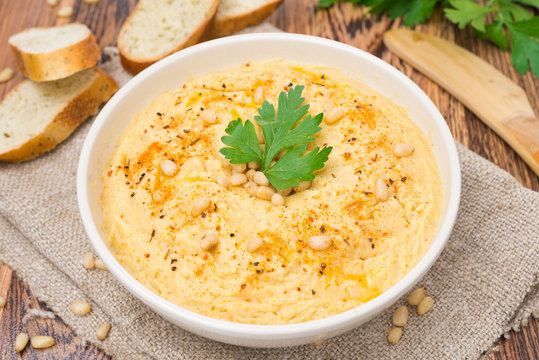 Hummus with pine nuts in a bowl, horizontal