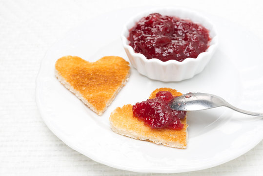 toast in the shape of hearts and berry jam on the plate