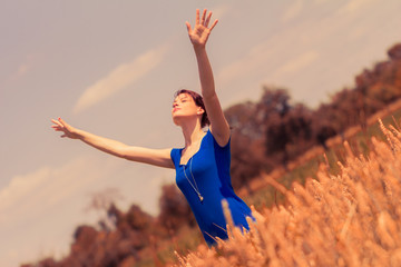 Beautiful young woman with hands up enjoying sun in nature