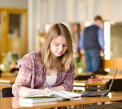 female student with laptop working in library