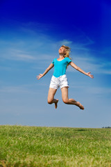 Fototapeta na wymiar happy woman jumps in a summer green field against the blue sky..