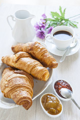 Croissants on table with jam and coffee