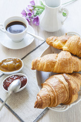 Croissants on table with jam and coffee
