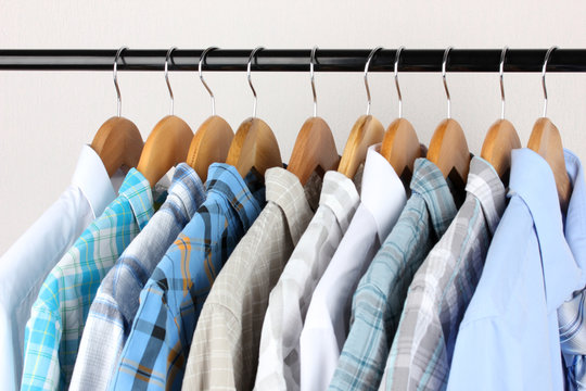 Shirts with ties on wooden hangers on light background