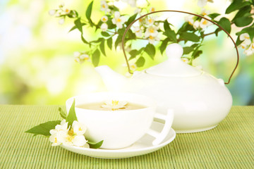 Fototapety  Filiżanka herbaty z jaśminem, na macie bambusowej, na jasnym tle