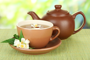 Cup of tea with jasmine, on bamboo mat, on bright background