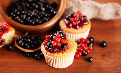 Tasty muffins with berries on wooden table
