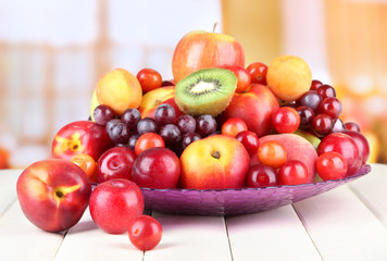 Assortment of juicy fruits on wooden table, on bright