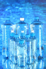 Water in different bottles on blue background