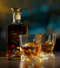 Glass of whiskey with bottle, on dark background