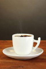 Cup of coffee on wooden table on black background