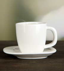 Cup of coffee on wooden table on bright background