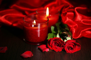 Naklejka premium Piękna romantyczna czerwona świeca z kwiatami i jedwabnym materiałem,