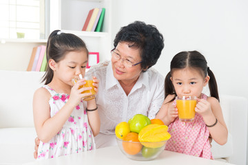 Asian children drinking orange juice