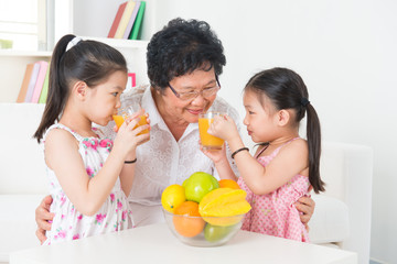 Obraz na płótnie Canvas Asian family drinking fresh orange juice