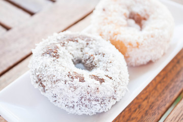 Chocolate and vanilla coconut donuts on wooden table