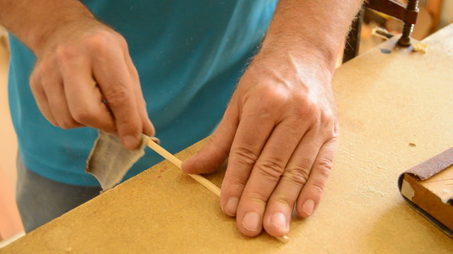 Luthier sanding a guitar piece