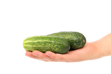 Hand holds two cucumbers.