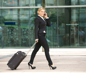 Young business woman walking and talking on phone in the city