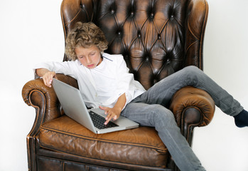 Junge entspannt mit Laptop auf Sessel