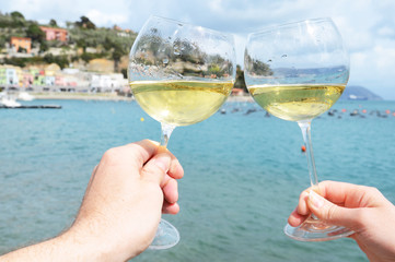 Two wineglasses in the hands against the harbour of Portvenere,