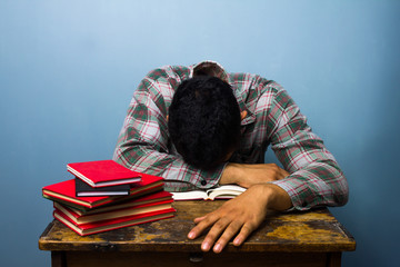 Fototapeta na wymiar Young man sleeping at desk after studying