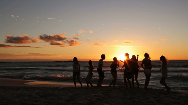 Group Of Young Hipster People dancing At Beach Party on sunset.