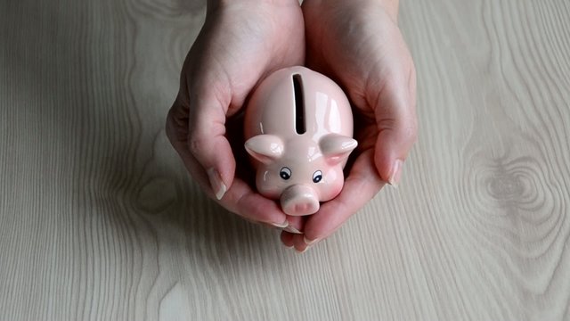 Una chica mostrando un cerdito hucha en sus manos