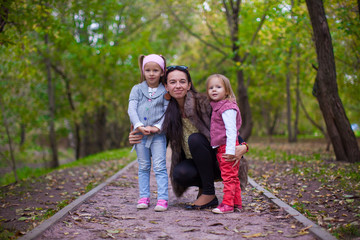 Young mother with her little daughters looking to camera oudoor